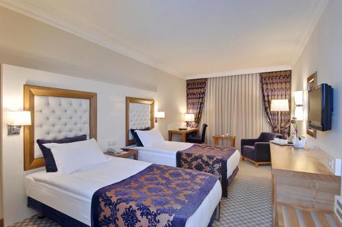 a hotel room with two beds and a desk at Tugcu Hotel Select in Bursa