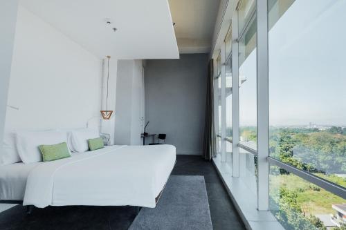 - une chambre avec un lit blanc et une grande fenêtre dans l'établissement Janevalla Bandung, à Bandung