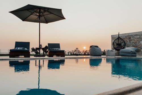 una piscina con sillas, una sombrilla y la puesta de sol en TheLuxuryVillas, en Preveza