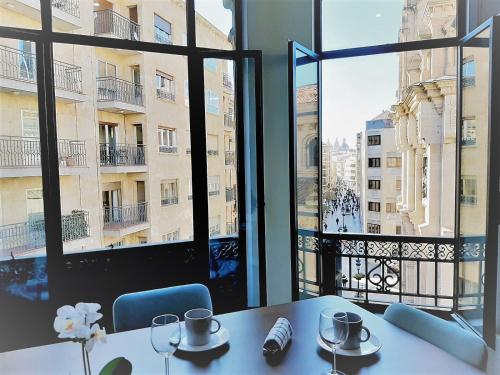 einen Tisch in einem Zimmer mit einem großen Fenster in der Unterkunft Apartamentos Vega by gaiarooms in Salamanca