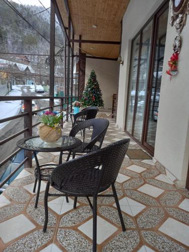 eine Terrasse mit Stühlen, einem Tisch und einem Weihnachtsbaum in der Unterkunft Guest House IVO in Bordschomi