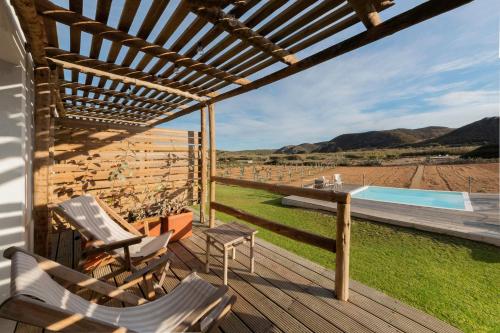 eine Terrasse mit Stühlen, einem Tisch und einem Pool in der Unterkunft Hortas do Rio - Casa de Campo in Carrapateira