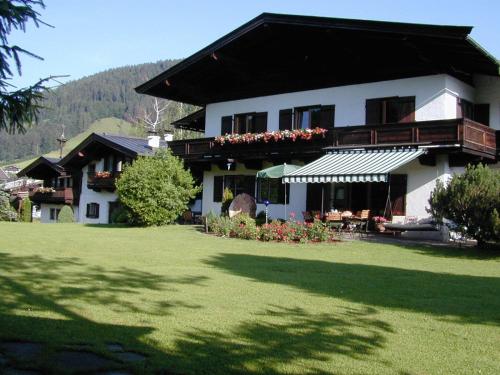 une grande maison blanche avec une pelouse devant elle dans l'établissement Pension Landhaus Gasteiger, à Kitzbühel