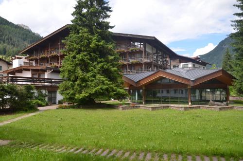 een groot gebouw met een boom ervoor bij Hotel Trento in Pozza di Fassa