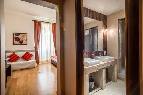 un bagno con lavandino e una camera da letto con divano di Hotel Everest Inn Rome a Roma