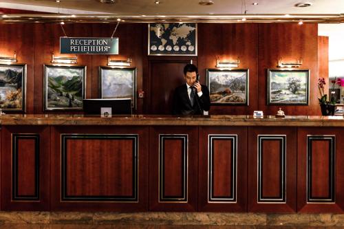 a man talking on a cell phone at a bar at Rahat Palace Hotel in Almaty