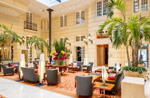 - un hall avec des chaises, des tables et des palmiers dans l'établissement Hotel Polonia Palace, à Varsovie