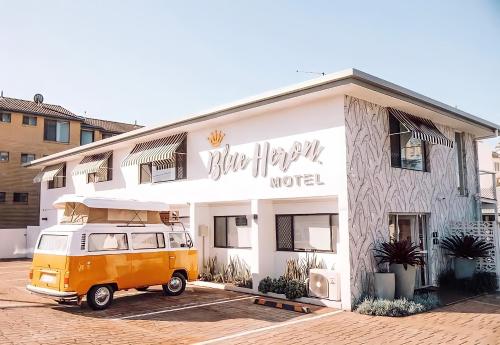 een oranje busje geparkeerd voor een gebouw bij Blue Heron Boutique Motel in Gold Coast