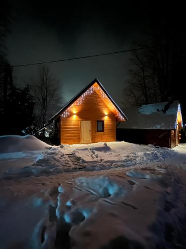 uma casa coberta de neve à noite com luzes em Poncyljuszówka em Szczyrk