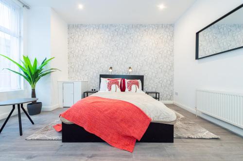 una camera con un letto con una coperta rossa di The Blossoms Studio Apartments a Liverpool