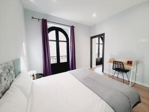 ein Schlafzimmer mit einem großen weißen Bett und einem Stuhl in der Unterkunft Apartamentos Vega by gaiarooms in Salamanca