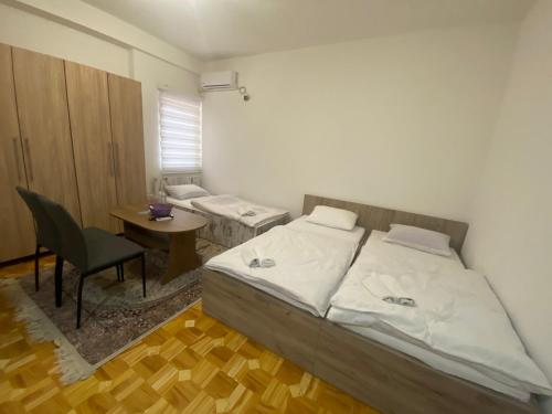 a bedroom with two beds and a table and a chair at Apartmani Hadžić in Živinice