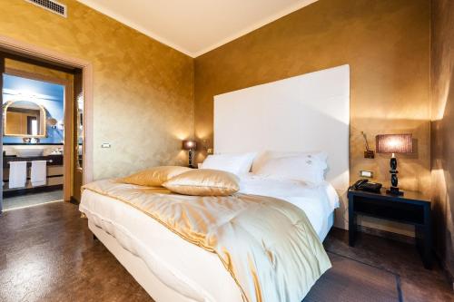 um quarto com uma grande cama branca e um espelho em Alla Corte Delle Terme Resort em Viterbo