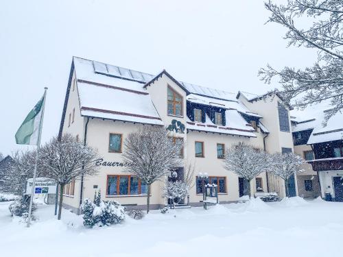 波滕施泰因Landhotel Bauernschmitt的一座被雪覆盖的建筑,前面有树木