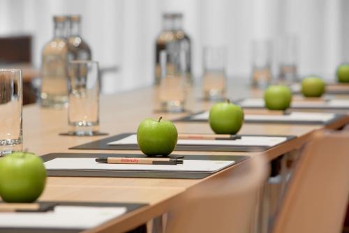 une rangée de tables avec des pommes vertes sur elles dans l'établissement IntercityHotel Wiesbaden, à Wiesbaden