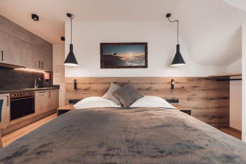 um quarto com uma cama grande e duas luzes pendentes em Alpenheim Apartment Ischgl em Ischgl