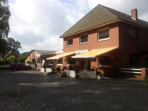 um edifício de tijolos com uma mesa e um guarda-chuva amarelo em Landhaus Wachendorf em Bruchhausen-Vilsen