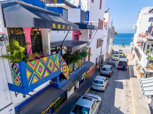 een stadsstraat met auto's geparkeerd voor gebouwen bij CASA MARÍA MALECÓN in Puerto Vallarta