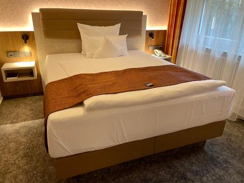 um quarto com uma cama grande e lençóis brancos em Hotel Merkur em Landstuhl