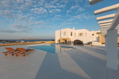 Villa Conza Mykonos في أغيوس يوانيس ميكونوس: مسبح مع كرسيين ومنزل