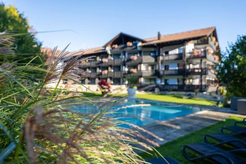 um hotel com piscina em frente a um edifício em Alpin & Wellness Resort Hotel Ludwig Royal em Oberstaufen