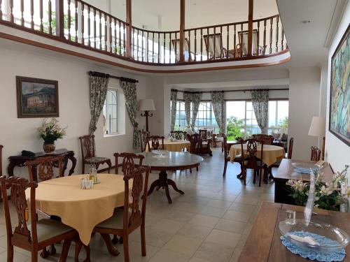 a restaurant with tables and chairs and a staircase at Beau Séjour Hotel in Victoria