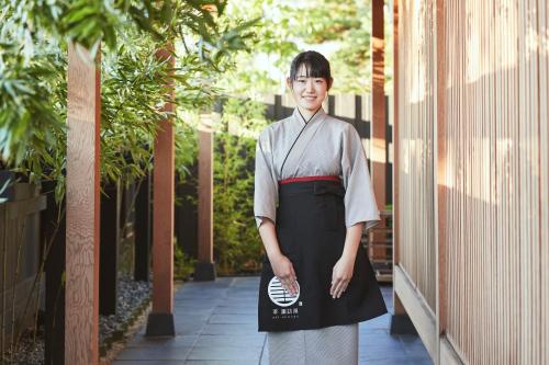 a woman in apron standing on a walkway at Sui Suwako in Suwa