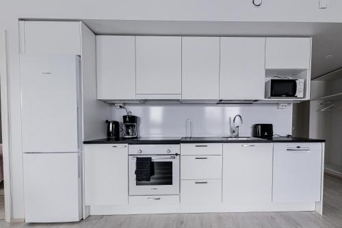 una cucina bianca con armadi bianchi e lavandino di Apartment, SleepWell, Nuutti a Turku