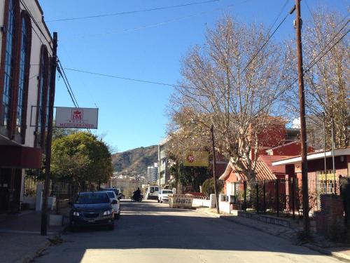 a street in a town with a car parked on the road at Hotel Mediterraneo in Villa Carlos Paz