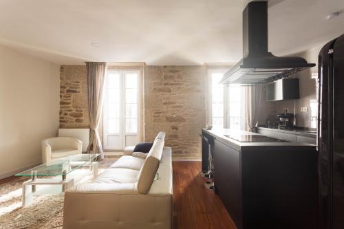 ein Wohnzimmer mit einem weißen Sofa und einer Küche in der Unterkunft Luxury apartment-free parking in Santiago de Compostela