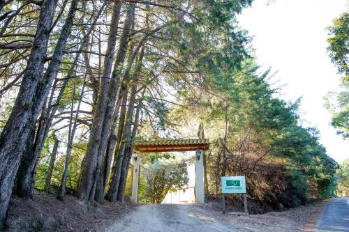 uma estrada com um portão no meio das árvores em Pousada Morro Verde em Águas de Lindóia