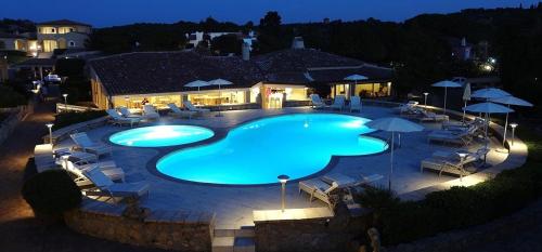 una gran piscina con sillas y sombrillas por la noche en Hotel Nibaru, en Porto Cervo