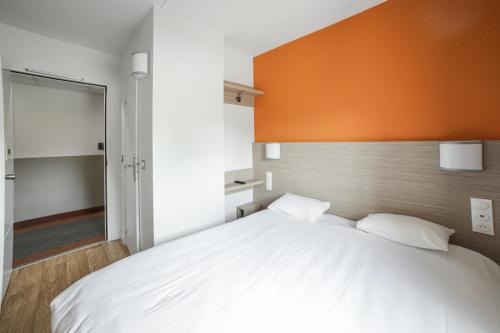 een slaapkamer met een groot wit bed met een oranje hoofdeinde bij Premiere Classe Valence - Bourg Les Valence in Bourg-lès-Valence