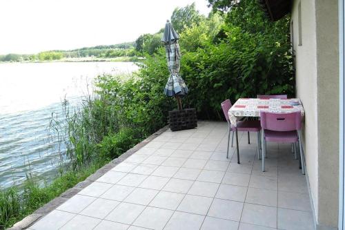 eine Terrasse mit einem Tisch, Stühlen und einem Sonnenschirm in der Unterkunft Holiday House in Szczecin at the lake with the terrace in Stettin