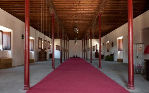 un largo pasillo con postes rojos y alfombra rosa en Quinta dos Álamos Agroturismo, en Golegã