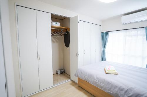 ein Schlafzimmer mit einem Bett und einem großen Schrank in der Unterkunft stay's サンジョイフル 303号 名古屋 民泊 駅近 in Nagoya