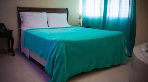 1 dormitorio con 1 cama con edredón verde en Hotel Luis V Santo Domingo, en Santo Domingo