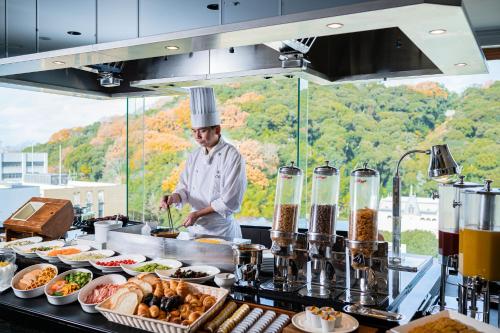 uno chef in piedi in una cucina che prepara il cibo di ANA Crowne Plaza Matsuyama, an IHG Hotel a Matsuyama