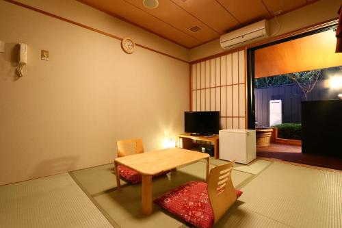 Cette chambre dispose d'une table, de chaises et d'une télévision. dans l'établissement リバティーリゾート久能山, à Komagoe