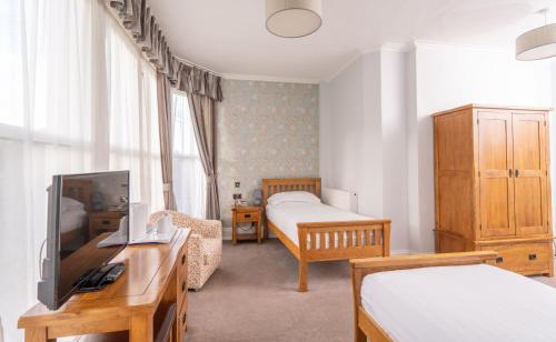 een slaapkamer met 2 bedden en een tv in een kamer bij Lauriston Hotel in Weston-super-Mare