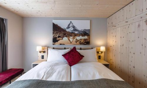 1 dormitorio con 1 cama blanca grande y 2 lámparas en Hotel Derby, en Zermatt