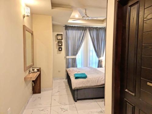 ein kleines Schlafzimmer mit einem Bett und einem Fenster in der Unterkunft Tranquil & Delightful 1 Bed Apt In Bahria Town in Rawalpindi