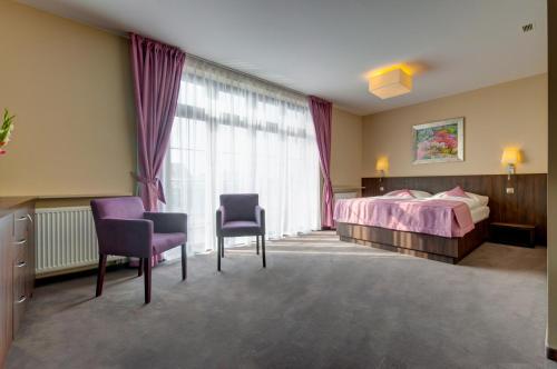 een slaapkamer met een bed en 2 stoelen en een raam bij Hotel Figa in Plewiska