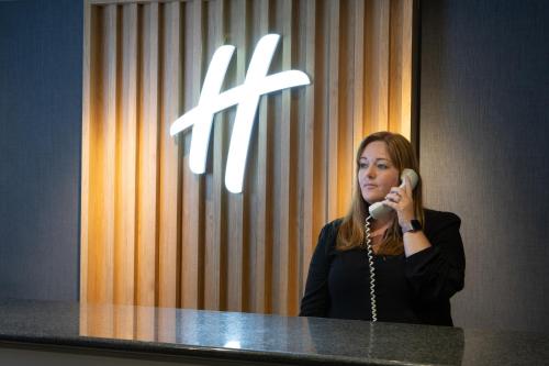 Una donna che parla al telefono davanti a uno specchio di Holiday Inn Bolton Centre, an IHG Hotel a Bolton