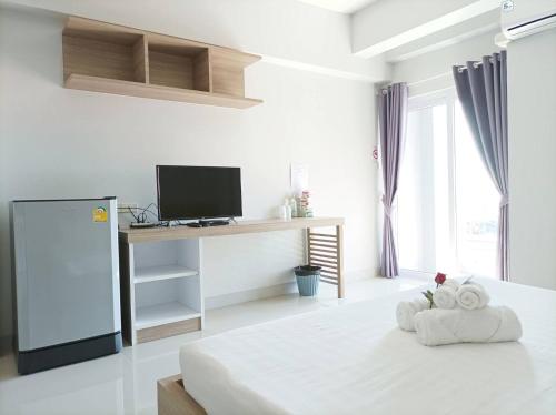 um quarto branco com uma cama e uma secretária com uma televisão em JVAPLACE em Nonthaburi