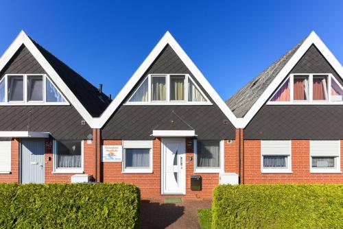 uma casa de tijolos vermelhos com telhado cinzento em Ferienhaus Nordlicht em Bensersiel