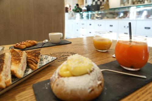 uma mesa com um prato de pão e dois copos de sumo de laranja em Trinity Luxury Rooms em Roma