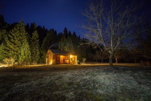 uma cabana no meio de um campo à noite em Wood Cabin by the River - for Nature Lovers em Vytina