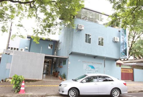 a white car parked in front of a blue building at Pousada Quedas D'água in Foz do Iguaçu