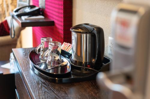 eine Kaffeemaschine und eine Brille auf dem Tisch in der Unterkunft Hotel Krebs Interlaken in Interlaken